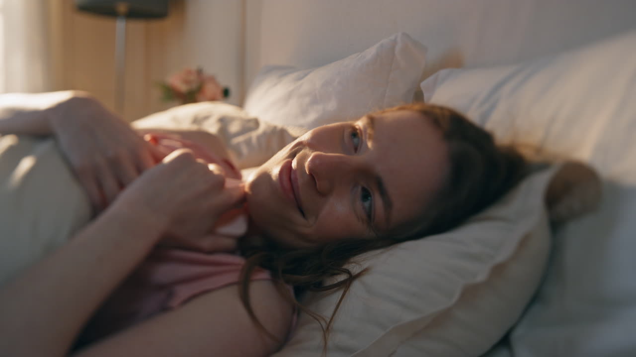 행복한 소녀가 침대에서 스마트폰 화면을 클로즈업합니다. 잠자는 여성은 메시지를 읽습니다.