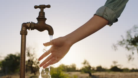 Frauenhände-Fangen-Wasser-Unter-Leitungswasser-Auf-Durstiger-Bauer-Trinkt-Süßwasser,-Das-Bei-Sonnenuntergang-Aus-Dem-Wasserhahn-Fließt,-Spart-Wasserkonzept