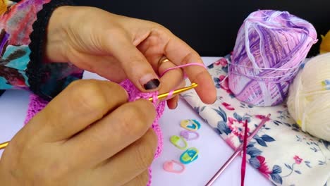 close-up-shot-of-professional-woman-hands-crocheting-dress-for-a-girl-by-hook-and-pink-wool