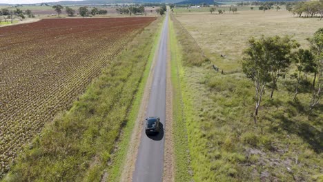 a car travels slowly through rural farmland