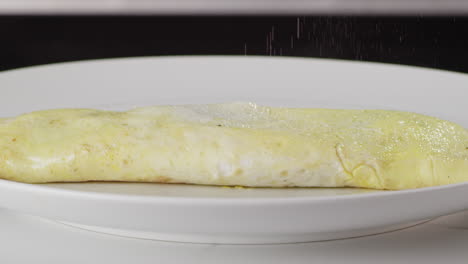 salting an egg omelette on a white plate