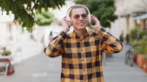 happy relaxed overjoyed man dancing in wireless headphones listening music on urban city street
