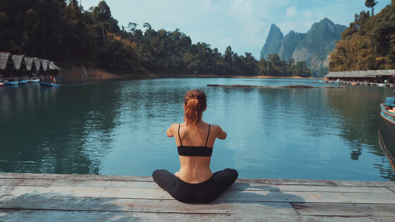 Woman practicing yoga by a lake