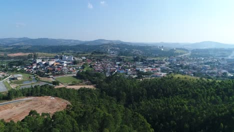 Beautiful-movement-ahead-with-Drone-filming-trees-in-the-foreground-and-arriving-in-a-small-town-in-the-countryside,-calm,-peace,-tranquility,-in-4K-resolution