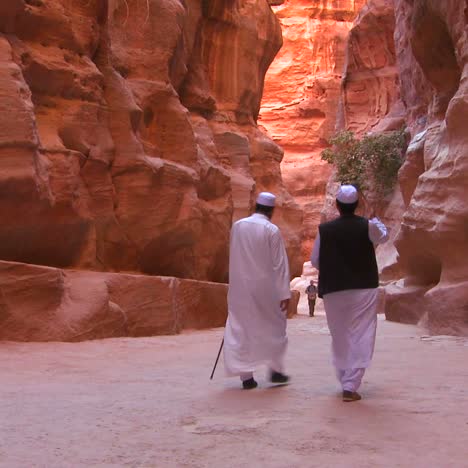 arab men walk through the narrow canyons leading up to petra jordan