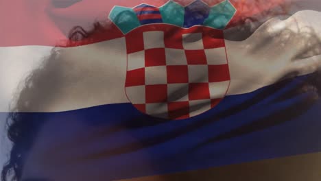 animation of croatia flag waving over happy african american woman with tousled curly hair