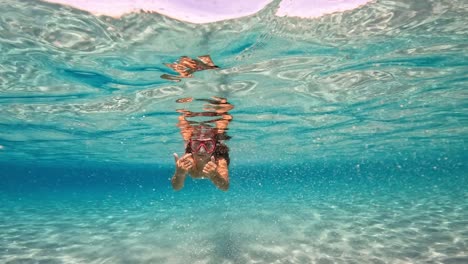 underwater scene of young redhead girl swimming undersea in crystal clear turquoise tropical sea water of exotic island