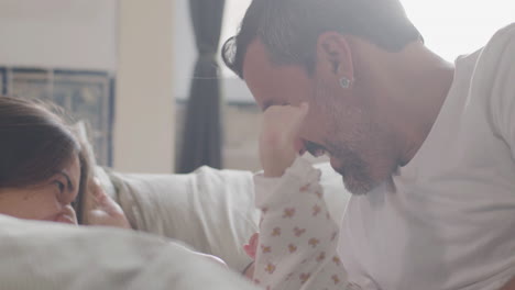 feliz pareja acostada en la cama el domingo por la mañana y jugando con su linda niña 2