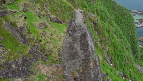 Filmische-Orbitale-Luftaufnahme-Eines-Bergsteigers-Auf-Dem-Gipfel-Des-Felsigen-Gipfels-Von-Svolvaergeita-Im-Frühling