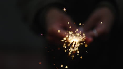 close-up-sparkler-woman-celebrating-new-years-eve-celebration-holding-festive-fireworks-at-night