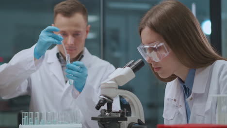 Un-Equipo-De-Científicos-Médicos-Está-Desarrollando-Una-Vacuna-Contra-El-Coronavirus-En-Un-Laboratorio-Médico,-Un-Hombre-Y-Una-Mujer-Están-Explorando-Virus-Y-Bacterias-Experimentando-Con-Medicamentos