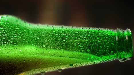 refreshing beer pouring out of the green bottle covered with water droplets, slow motion