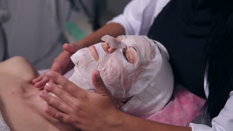 Close-Up-view-of-a-professional-cosmetologist-hands-making-neck-massage-to-the-young-woman-with-mask-on-her-face-and-neck