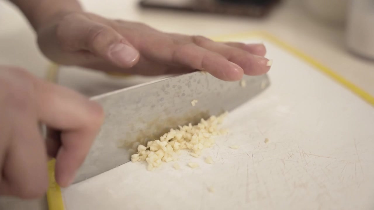 Caucasian hands chopping fresh garlic, raw food, cooking