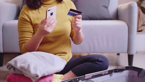 woman booking flight online with her cell phone and credit card for travel in the summertime