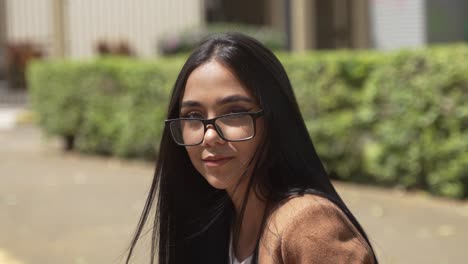 Beautiful-Green-Eyed-Latina-Woman-Sitting-on-Sidewalk-Looking-Ahead-then-Straight-into-Camera