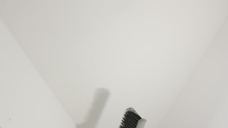 Cleaning cobwebs from ceiling of new apartment, dusty broom