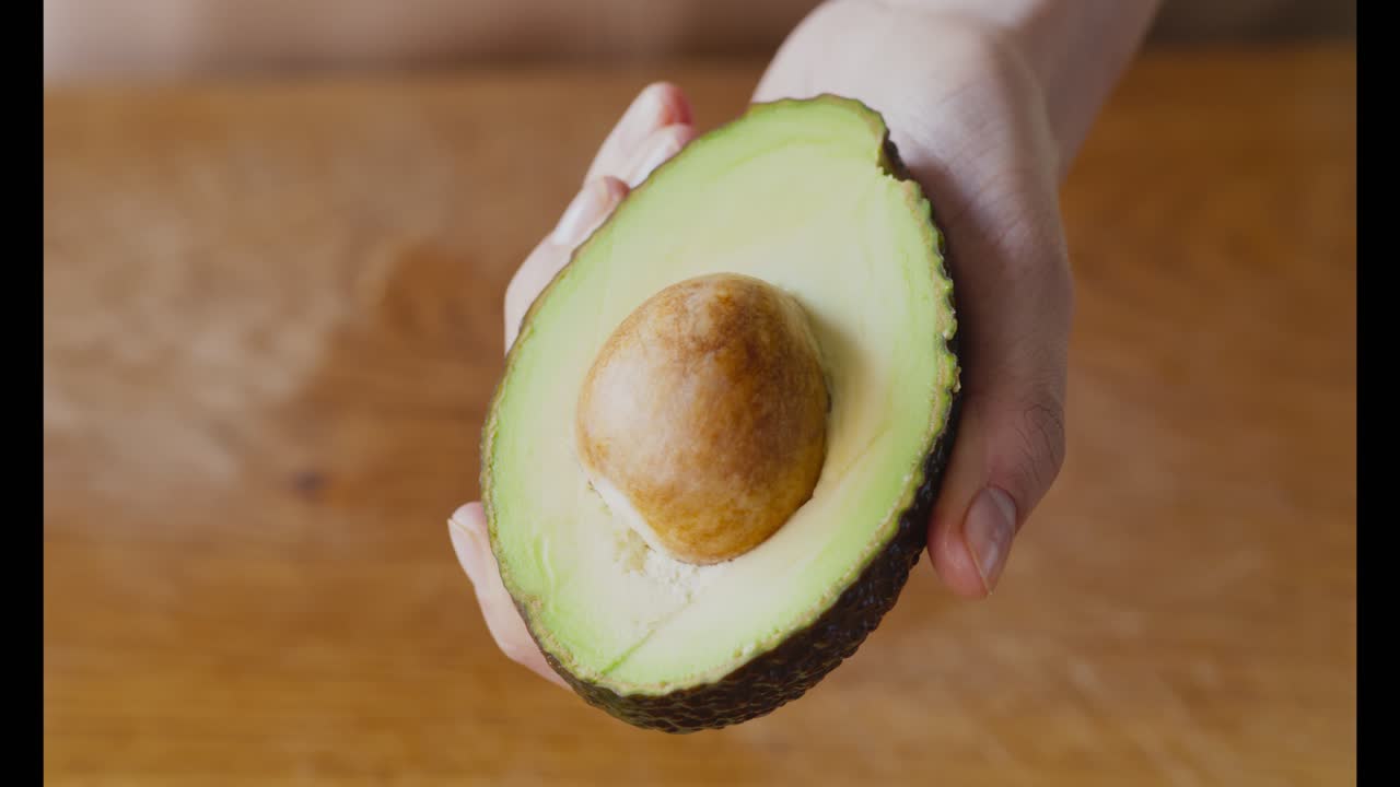 아보카도 의 절반 을 들고 있는 손
