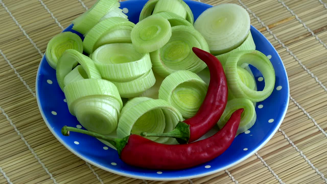 Rotating fresh chopped leeks and red hot chili peppers