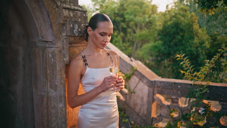 mujer glamurosa refrescando vino en el antiguo palacio. dama chic sosteniendo un vaso de vino
