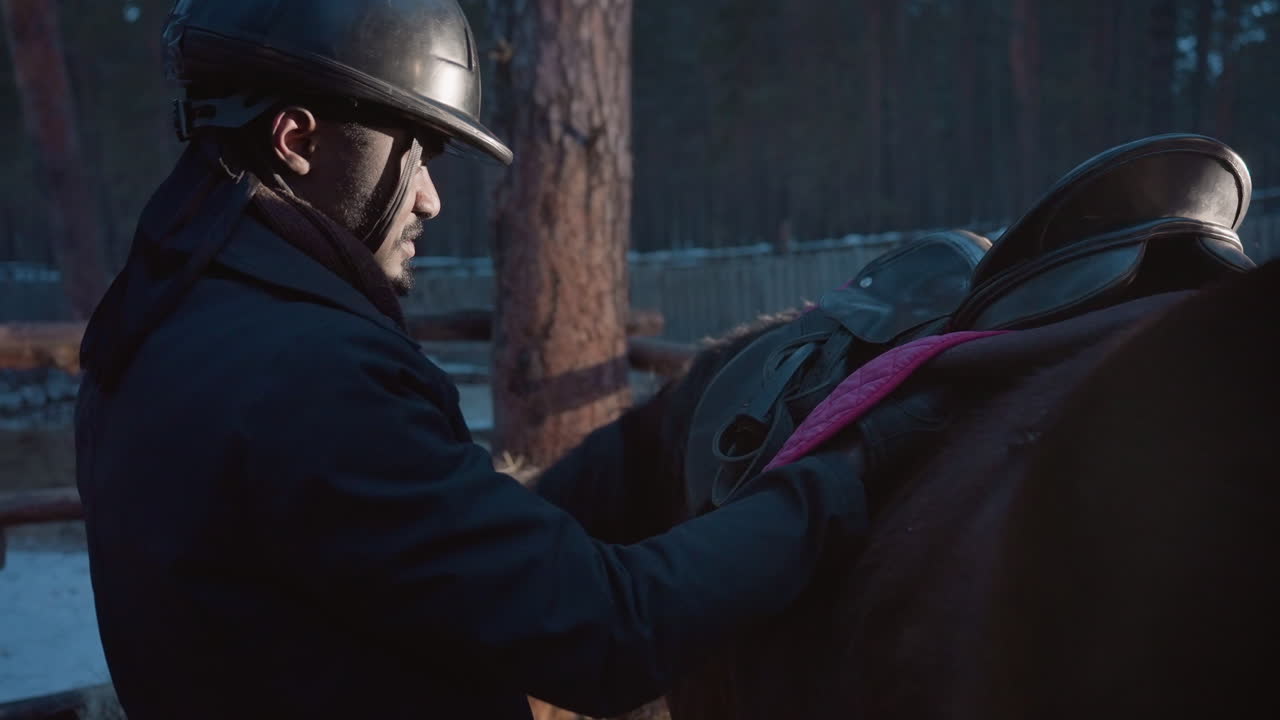 Ajustando los estribos antes de montar, escena tranquila al atardecer con jinete atento, centrado en los ajustes de la silla al anochecer en la granja, entorno sereno al crepúsculo donde el jinete prepara cuidadosamente el equipo cerca del caballo