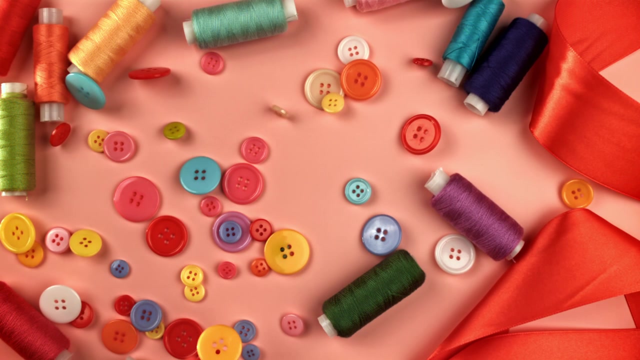 Colorful Sewing Buttons Falling and Scattering on a Pink Background