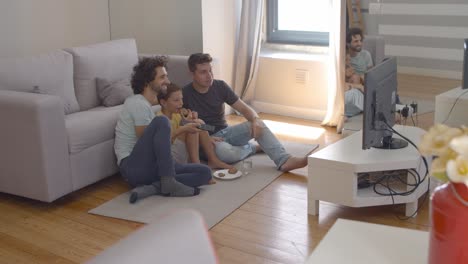 gay parents and child eating cookies and watching movie