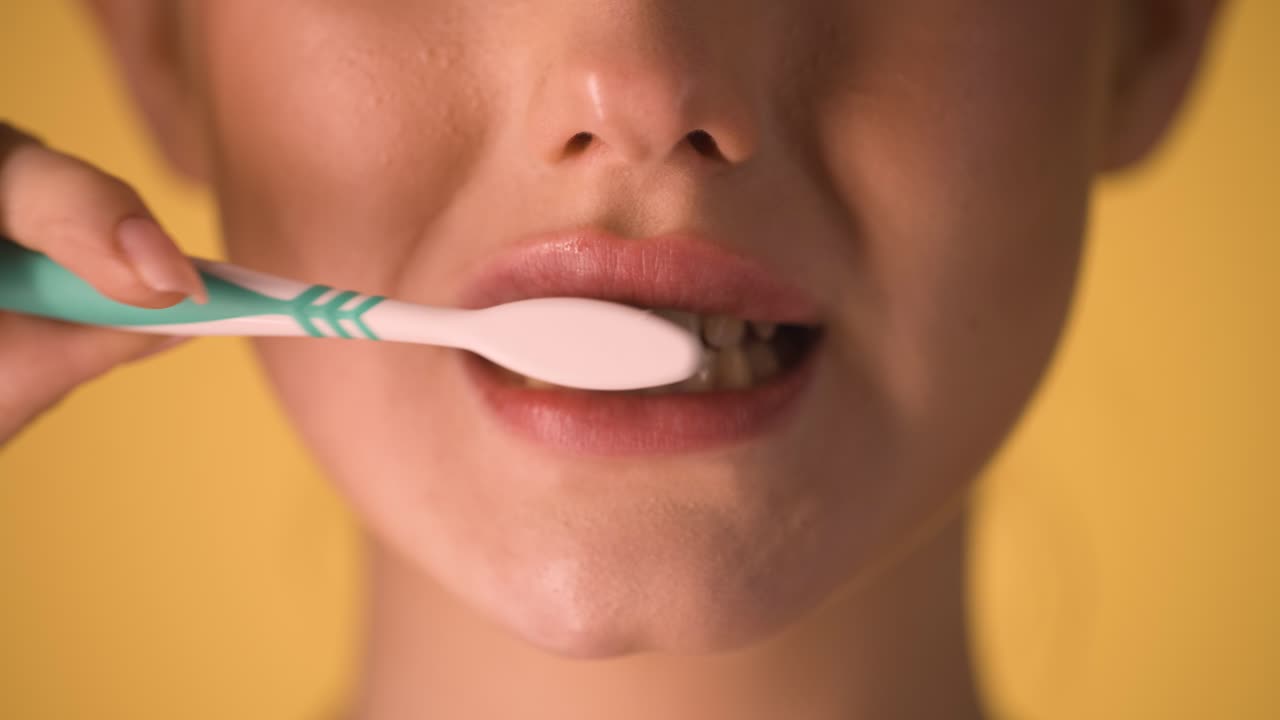 mujer joven caucásica se cepilla los dientes con cepillo de dientes boca de primer plano croma foto de fondo, modelo femenina con maquillaje y labios brillantes