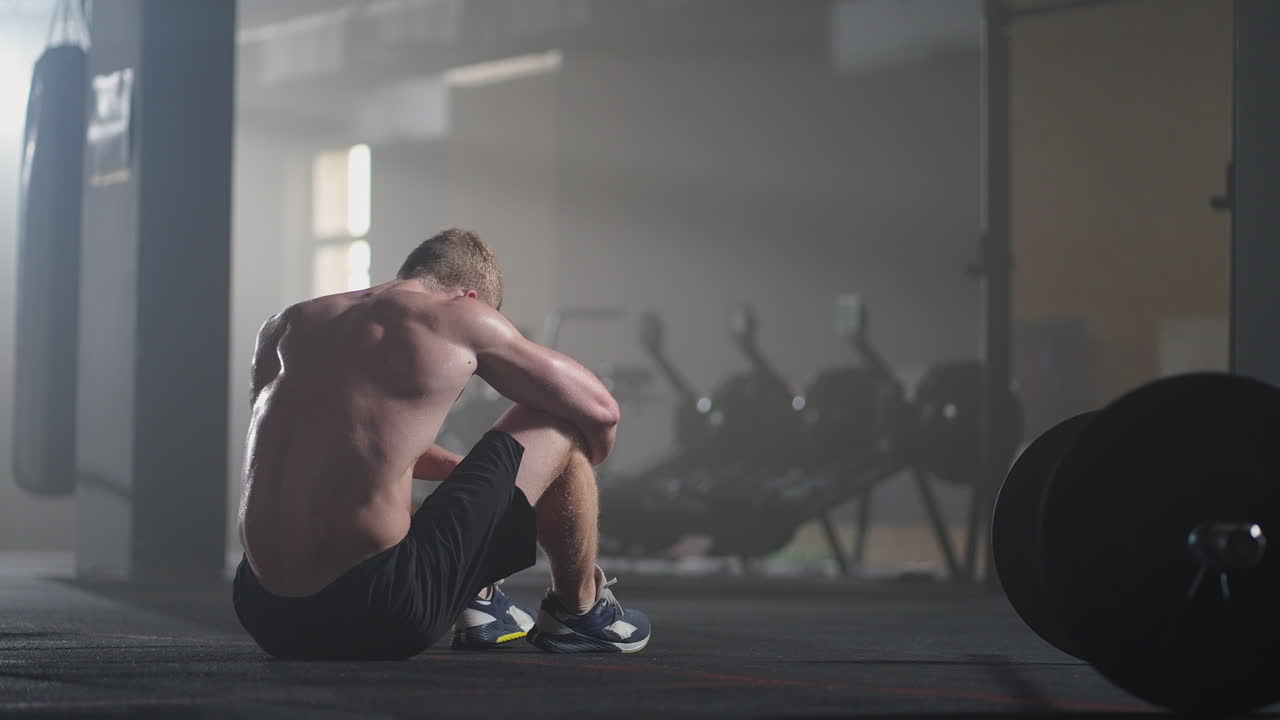 체육관에서 집중적인 운동을 한 후 휴식을 취하는 지친 젊은 남성. 체육관에서 근력 훈련 운동을 한 후 피곤한 건강한 남성. 강렬한 운동을 한 후 서서 휴식을 취하는 피곤한 남성 피트 모델.