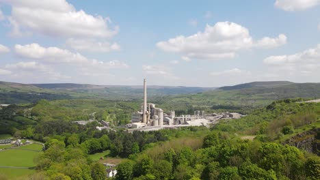 Vuelo-Aéreo-De-Drones-En-Dirección-Al-Edificio-Principal-De-Las-Obras-De-Cemento-Breedon-Hope-Con-Una-Vista-Panorámica-Del-Distrito-Peak-Circundante