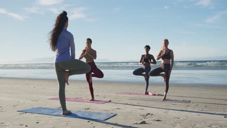 group of diverse female friends practicing yoga at the beach