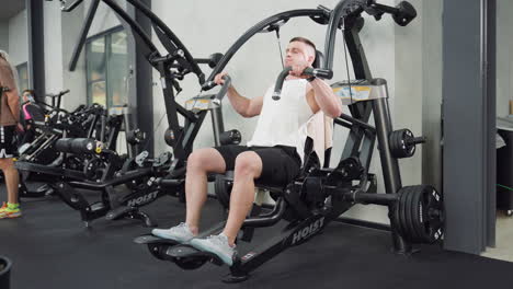 fitness enthusiast performs chest press motion then removes hand from handle mid rep on weight machine, muscles flexing and equipment steady in modern gym with bright lighting