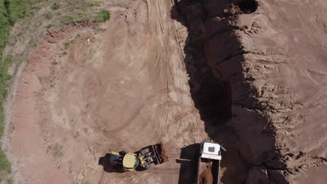 un disparo de drone de un excavador cargando en un camión en un desarrollo de propiedad