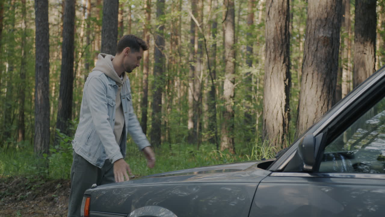 Man Fixing a Car in the Forest