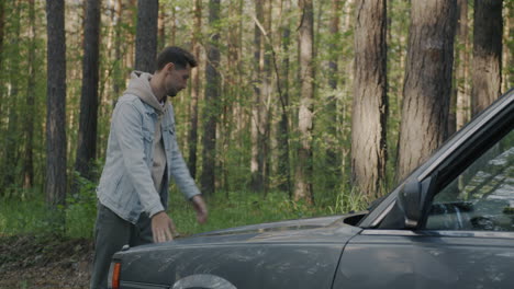 man fixing a car in the forest