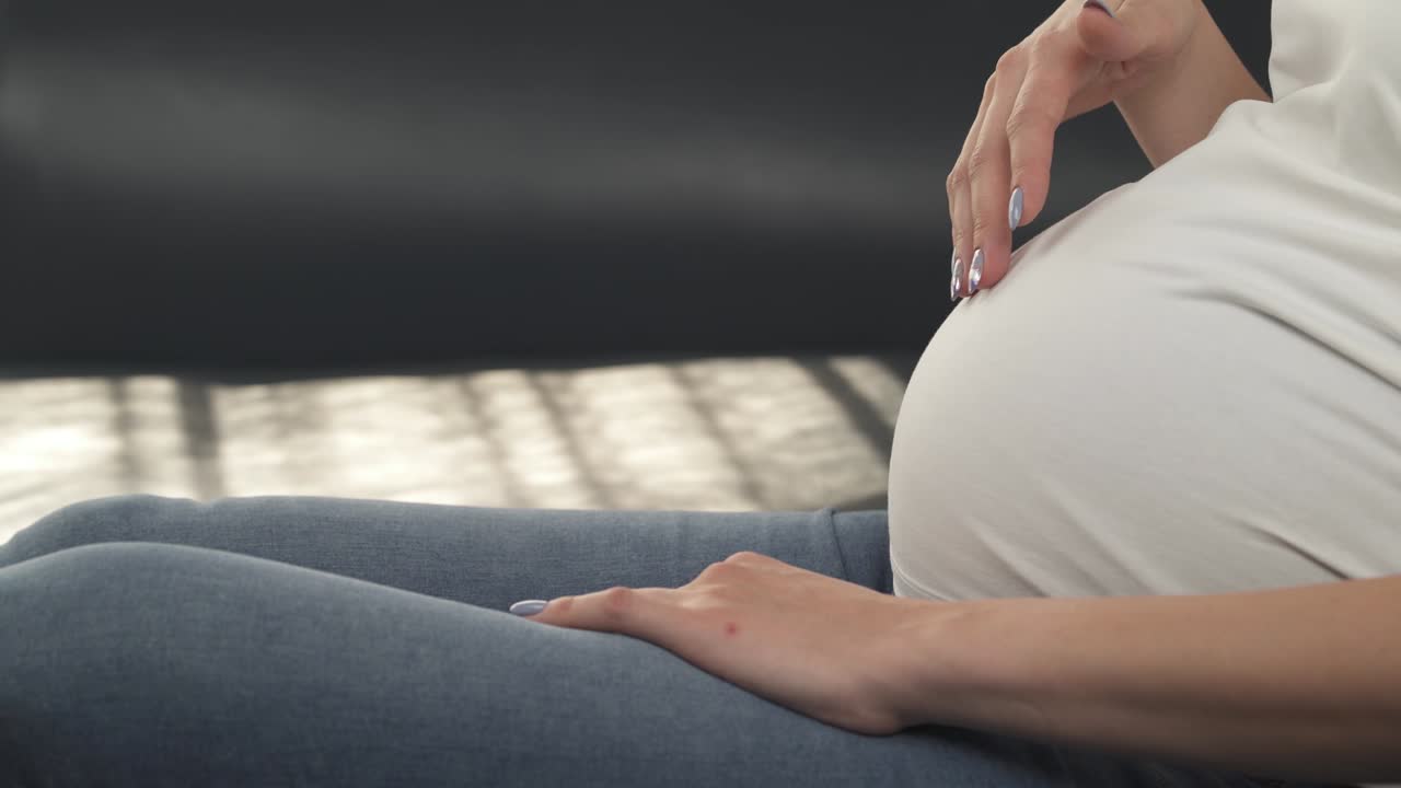 임산부의 배를 가까이 쳐다보는 모습: 손이 위쪽 아래쪽을 따라 움직이고, 카메라가 왼쪽에서 오른쪽으로 천천히 움직인다.