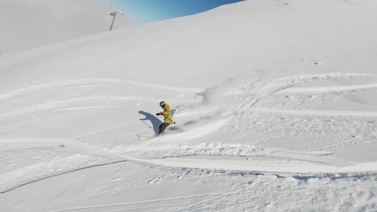 An exhilarating FPV drone shot capturing a snowboarder carving through deep powder snow on a bright winter day. The dynamic perspective highlights the snowboarder in the untouched snowy terrain