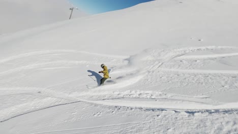 an exhilarating fpv drone shot capturing a snowboarder carving through deep powder snow on a bright winter day. the dynamic perspective highlights the snowboarder in the untouched snowy terrain