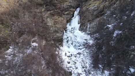 couple of climbers with backpack walking towards a frozen waterfall