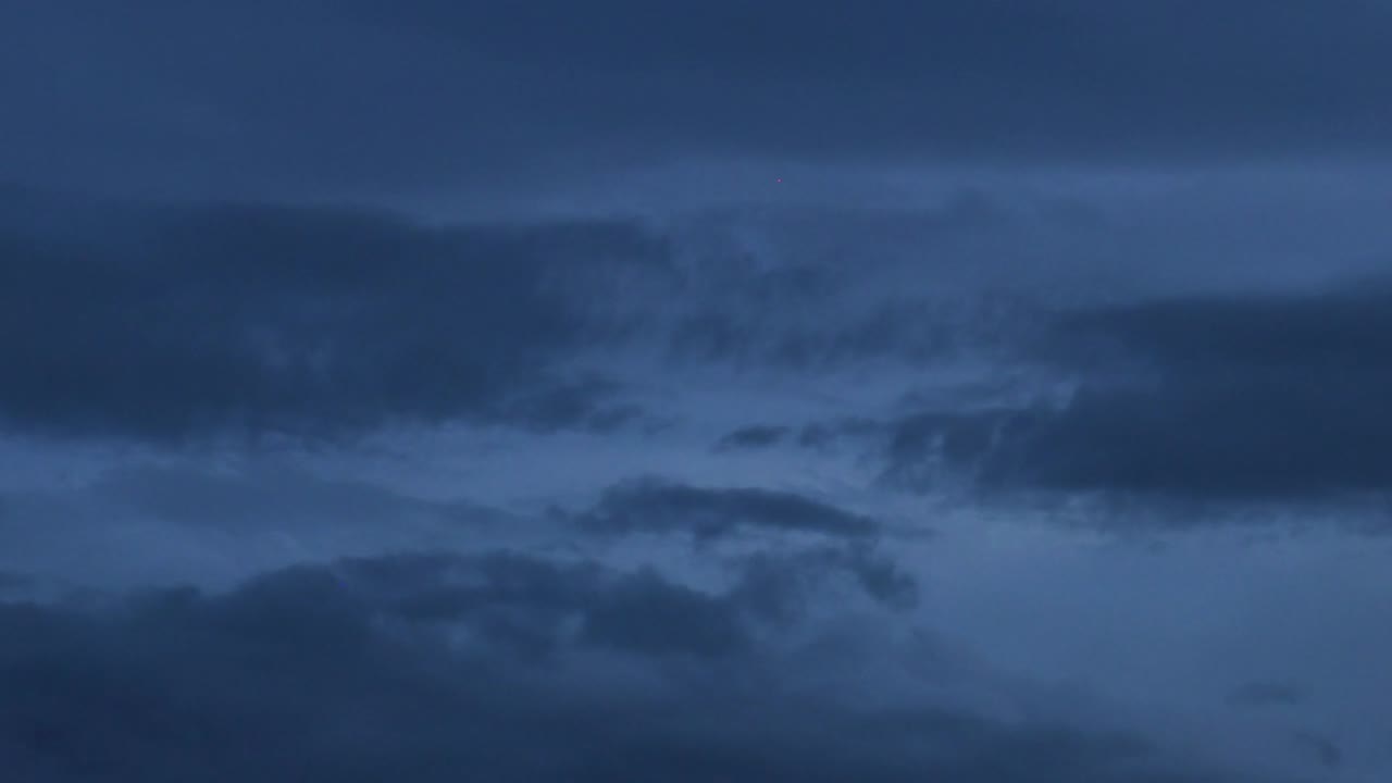 Observe the gradual shift of clouds as daylight fades into evening, showcasing a serene atmospheric change.