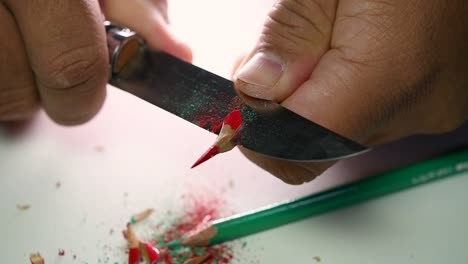 Footage-of-hands-slowly-sharpening-a-pencil-and-some-coloured-pencils-with-a-sharp-knife