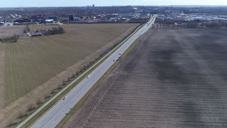 Highway-in-sweden-crosses-green-and-brown-agriculture-farmed-fields-on-the-side