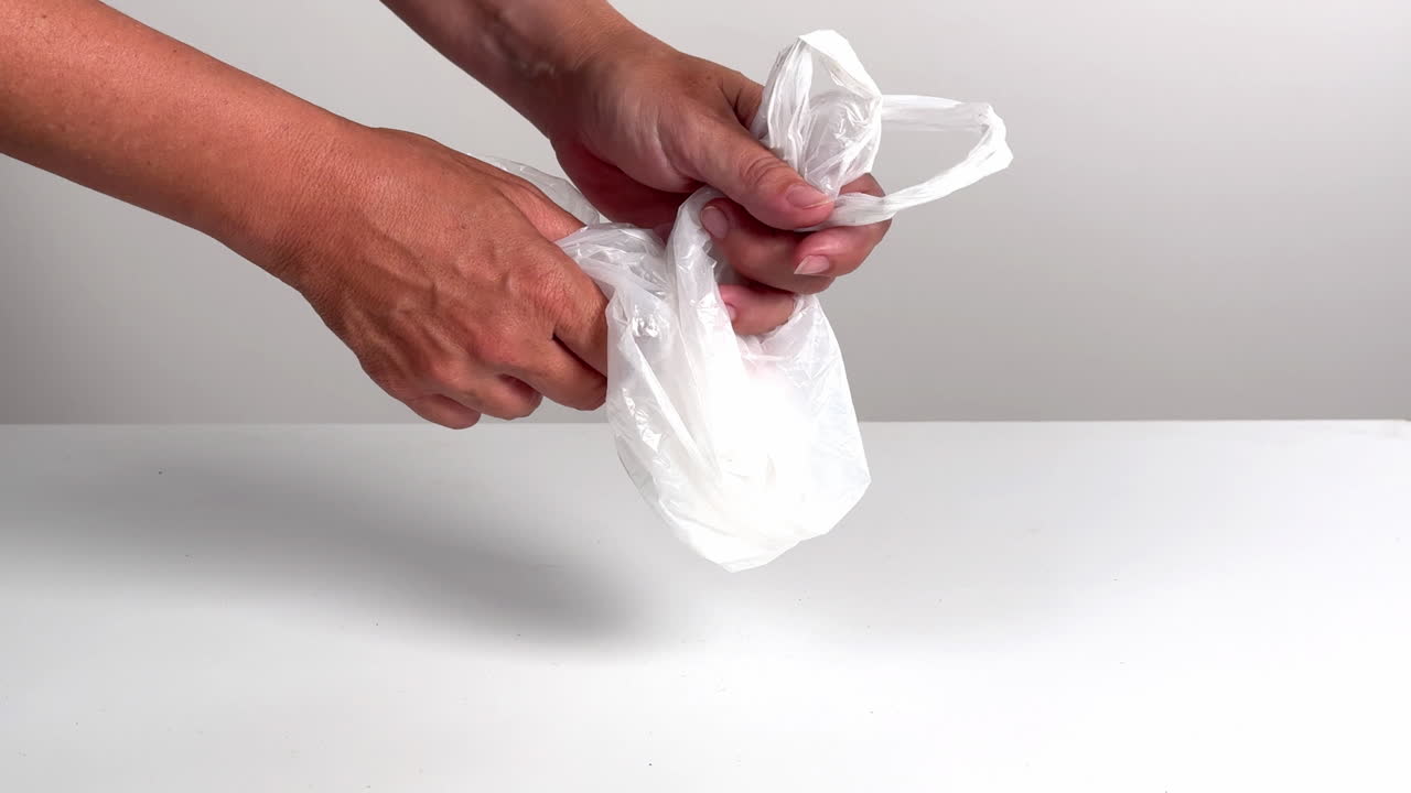Mani che stropicciano e allungano una busta di plastica bianca
