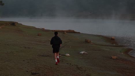 running workout on foggy lakeside trail, peaceful early morning scene outdoors