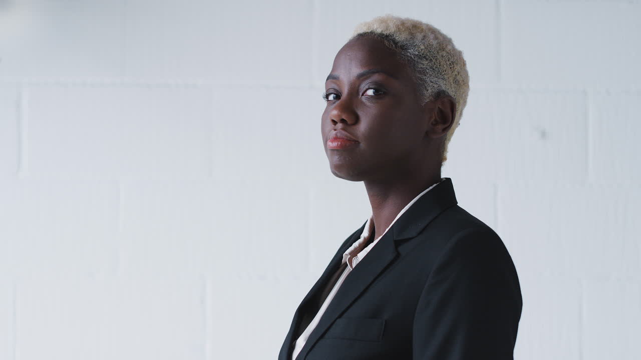 retrato de una joven mujer de negocios sonriente con traje de pie contra la pared del estudio blanco