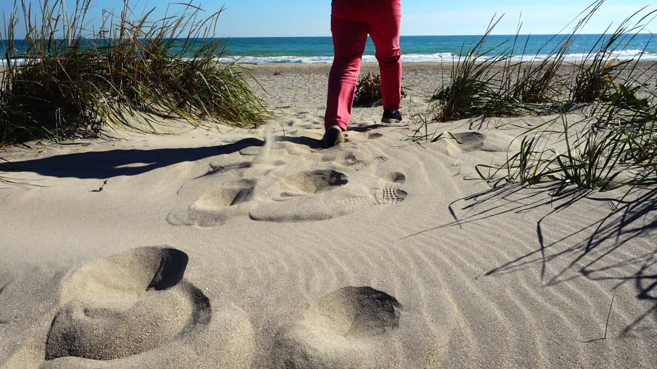 Kvinnen løper på sanddyner til havet. Sakte film.