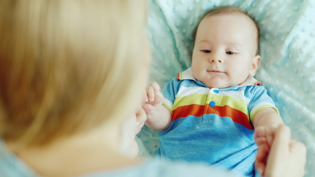 엄마는 아기와 함께 노는 두 달 된 소년 침대 뒷모습 어깨 여자