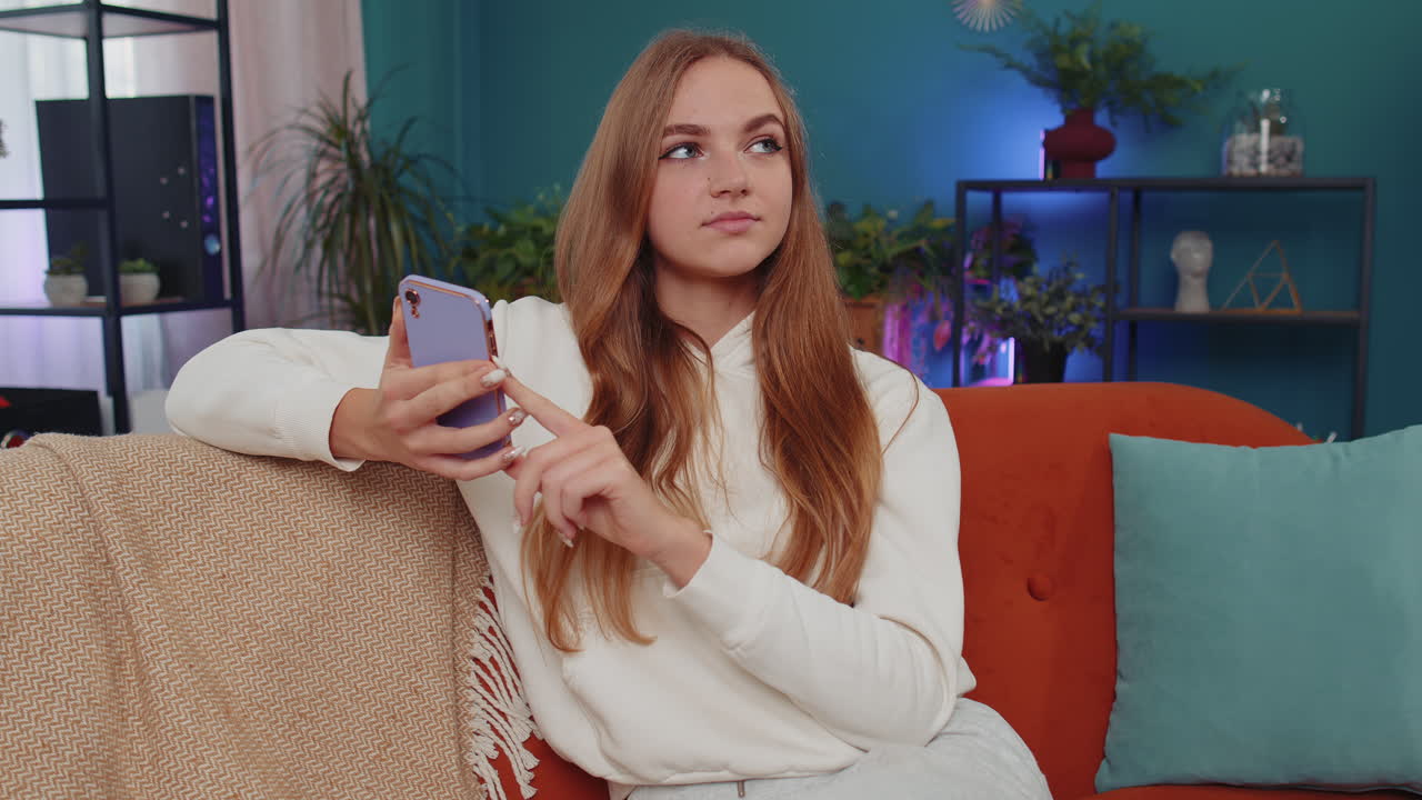 retrato de una niña adulta sentada en el sofá, usando un teléfono inteligente para compartir mensajes en aplicaciones de redes sociales