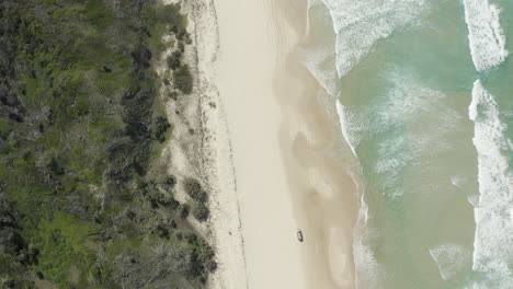 Toma-Aérea-De-4k-Siguiendo-A-Un-Auto-Conduciendo-A-Lo-Largo-De-La-Hermosa-Playa-En-La-Isla-Fraser,-Australia