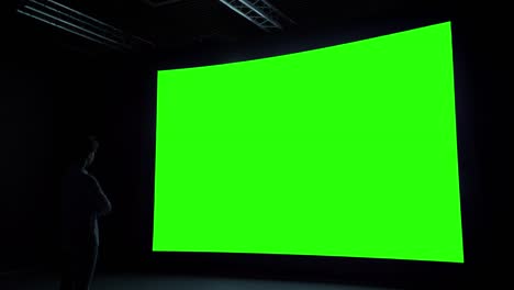 woman looking at blank large interactive wall display - green screen concept